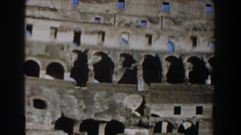 Visitor-shot 1959 8mm frame of the Roman Colosseum interior, showing arched bays, square openings, and worn stonework.