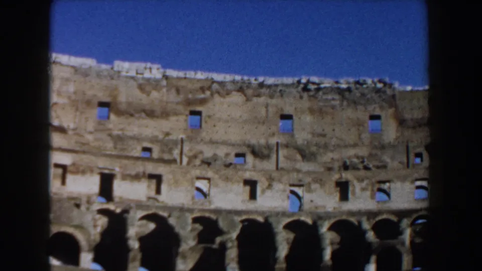 1959 Rome 8mm view of the Colosseum's interior wall, with rough upper masonry, arched openings, and blue sky.