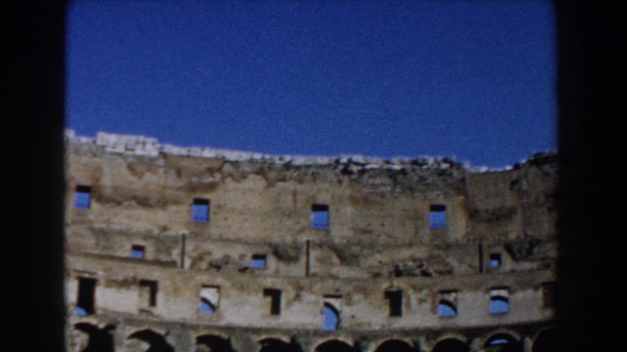 1959 8mm view inside Rome's Colosseum showing weathered upper masonry, arched openings, and a clear blue sky.