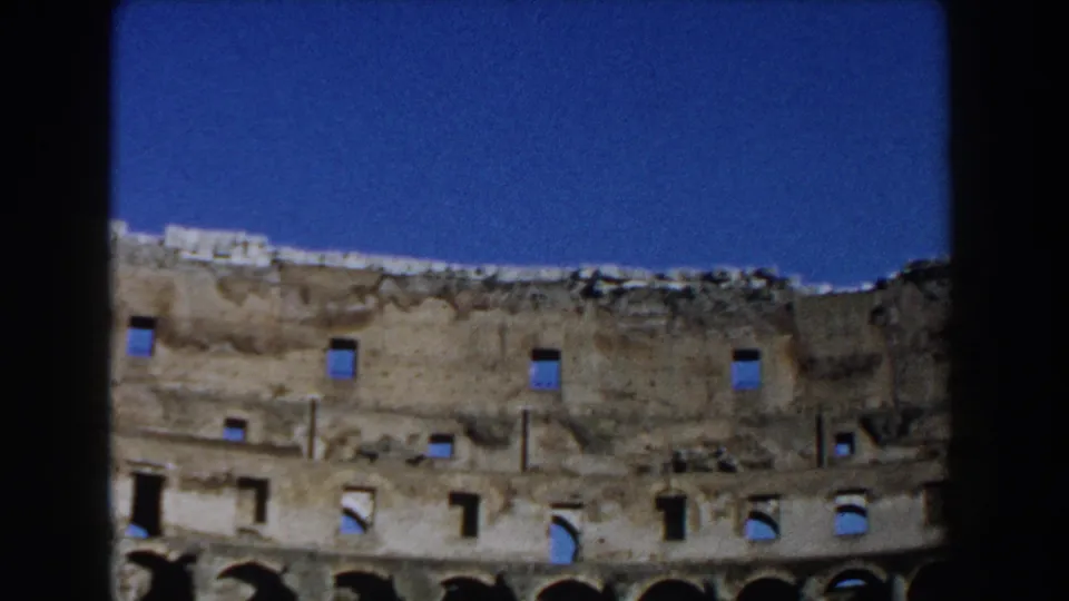1959 8mm view inside Rome's Colosseum showing weathered upper masonry, arched openings, and a clear blue sky.