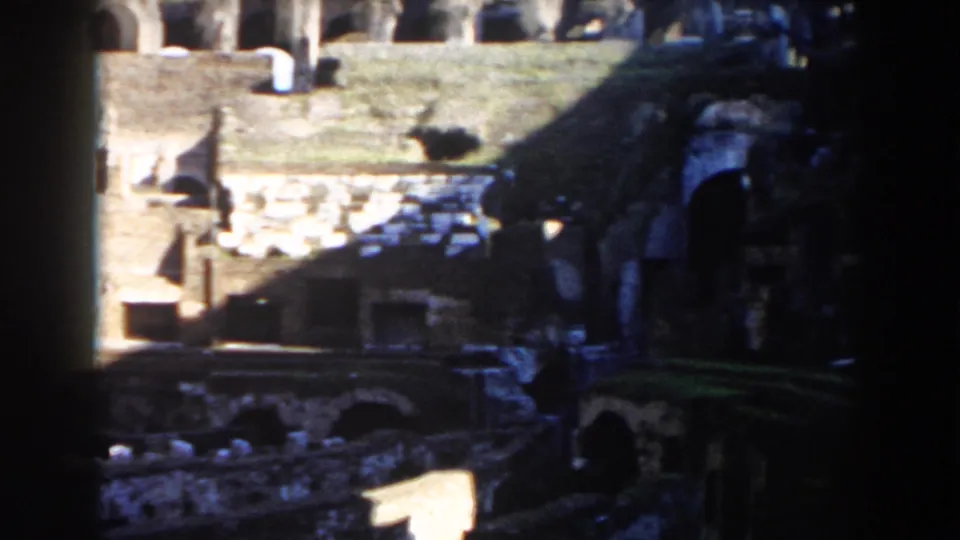 Rome Colosseum ruins on 8mm film, with bright upper grass, dark lower arches, and worn stone surfaces.