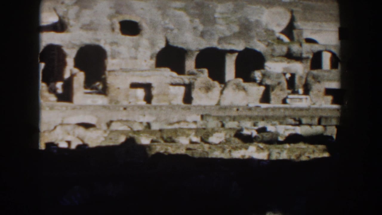 1959 Rome home-movie view of the Colosseum's weathered arches and stonework framed by dark film borders.