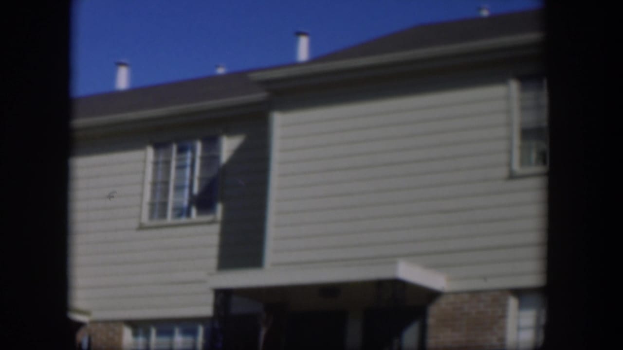 Two-story light-sided house with windows under a blue sky.