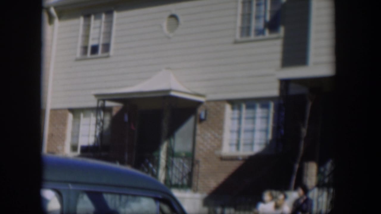 Townhouse exterior partly blocked by a blue parked car.