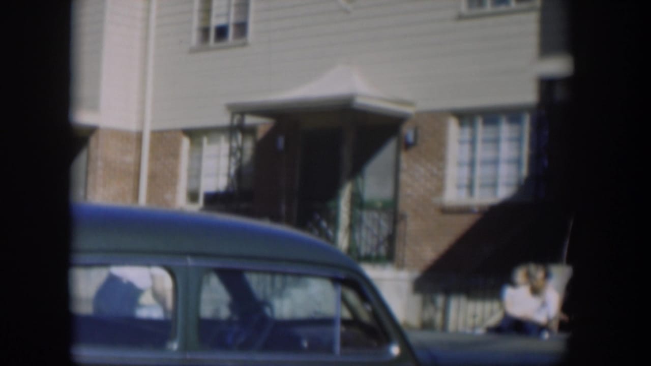 Blue car in front of townhouse entrances and windows.