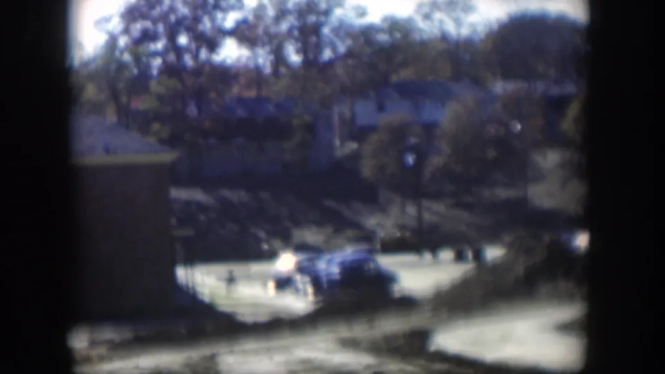 Blue sedan and another car appear near a low apartment building in the supplied 1954 Nevada residential scene.