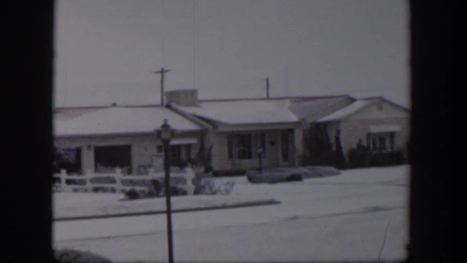 Snow-covered Nevada residential street with a low house, white fence, streetlamp, and no people visible.