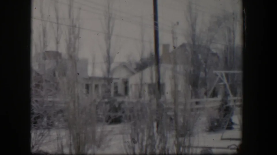 Soft 8mm Nevada winter view showing snow, utility lines, a modest building, bare trees, and a wooden structure to the right.