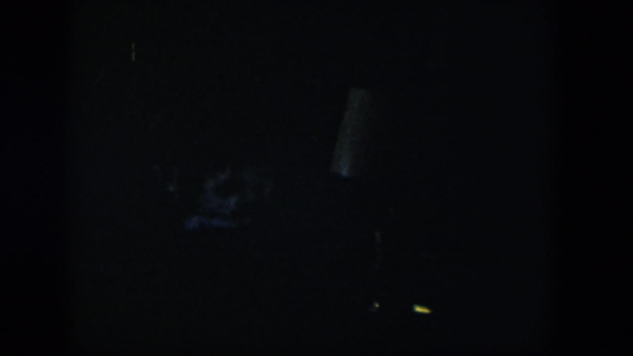 Very dark room with faint blue-gray shapes and minimal detail.