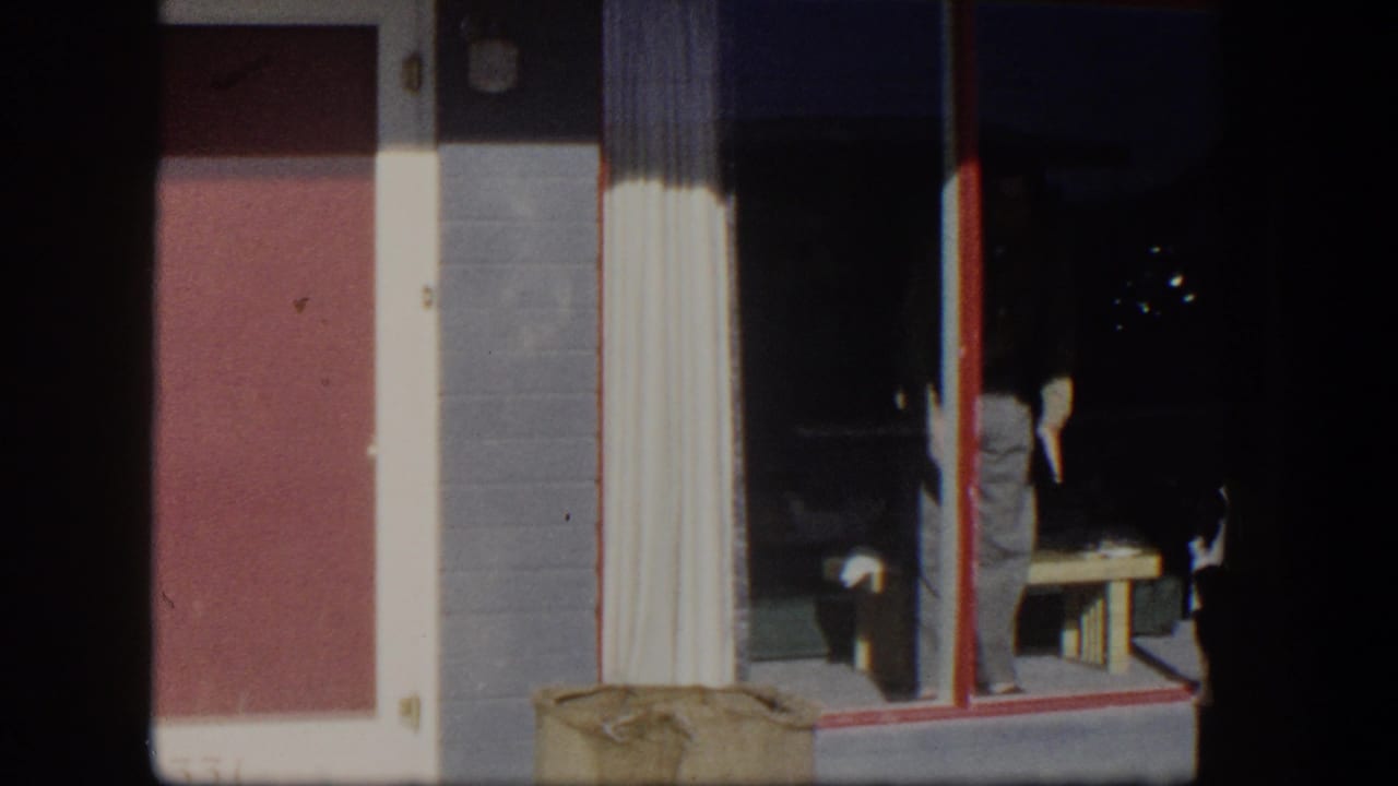 Exterior wall with red door and glass doorway, with a man partly visible inside.