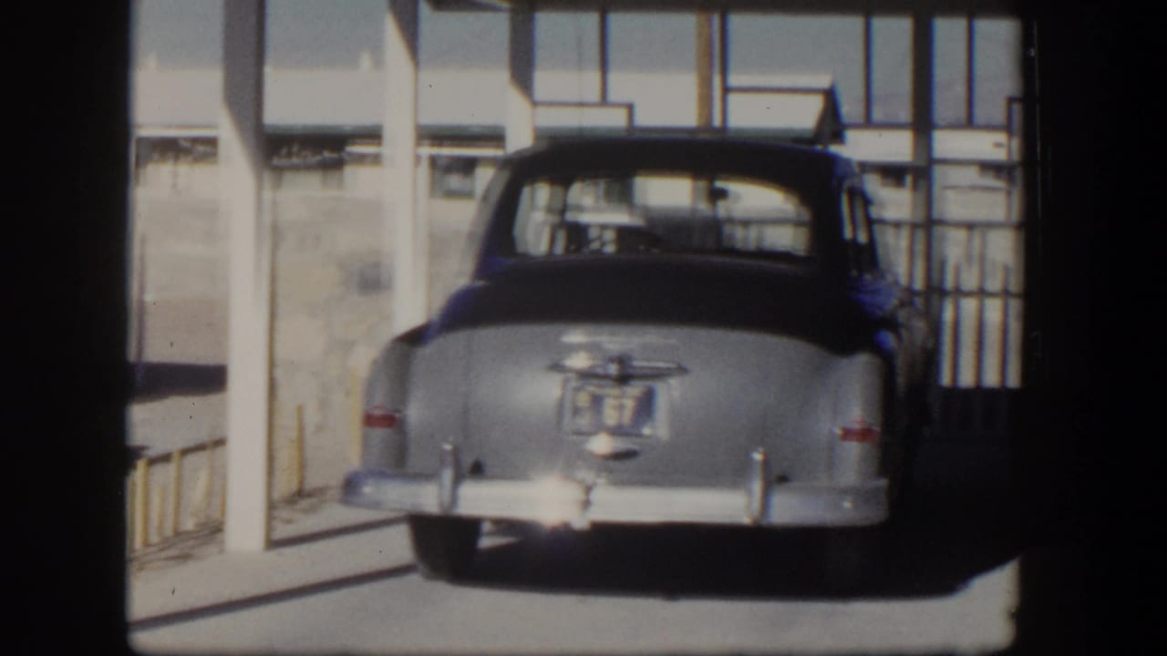 Older rounded car parked beside a light-colored house exterior.