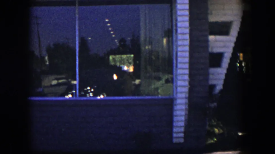 Blue-toned 1954 Nevada frame of the storefront facade, including a large window, reflections, brickwork, and a side wall edge.