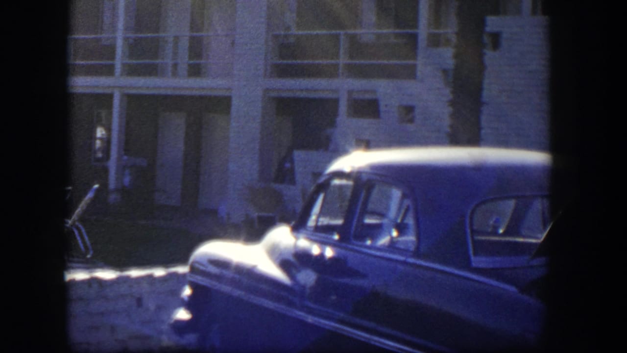Vintage car parked outside a modern building in strong blue-toned shade.