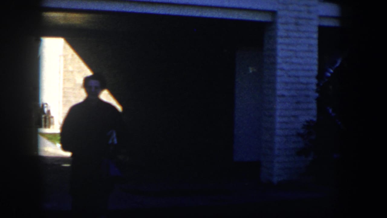 Silhouetted woman standing near a garage opening with bright exterior light behind her.