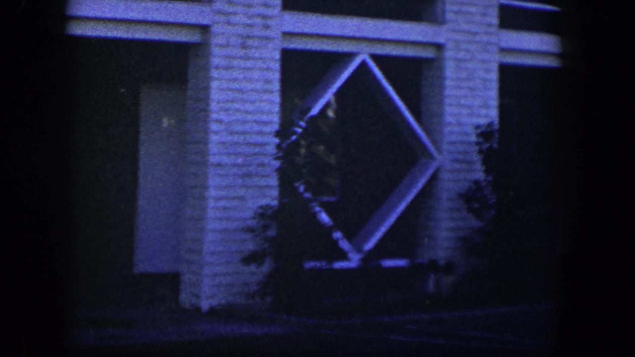 White brick facade with a diamond-shaped lattice frame and shrubs at dusk.