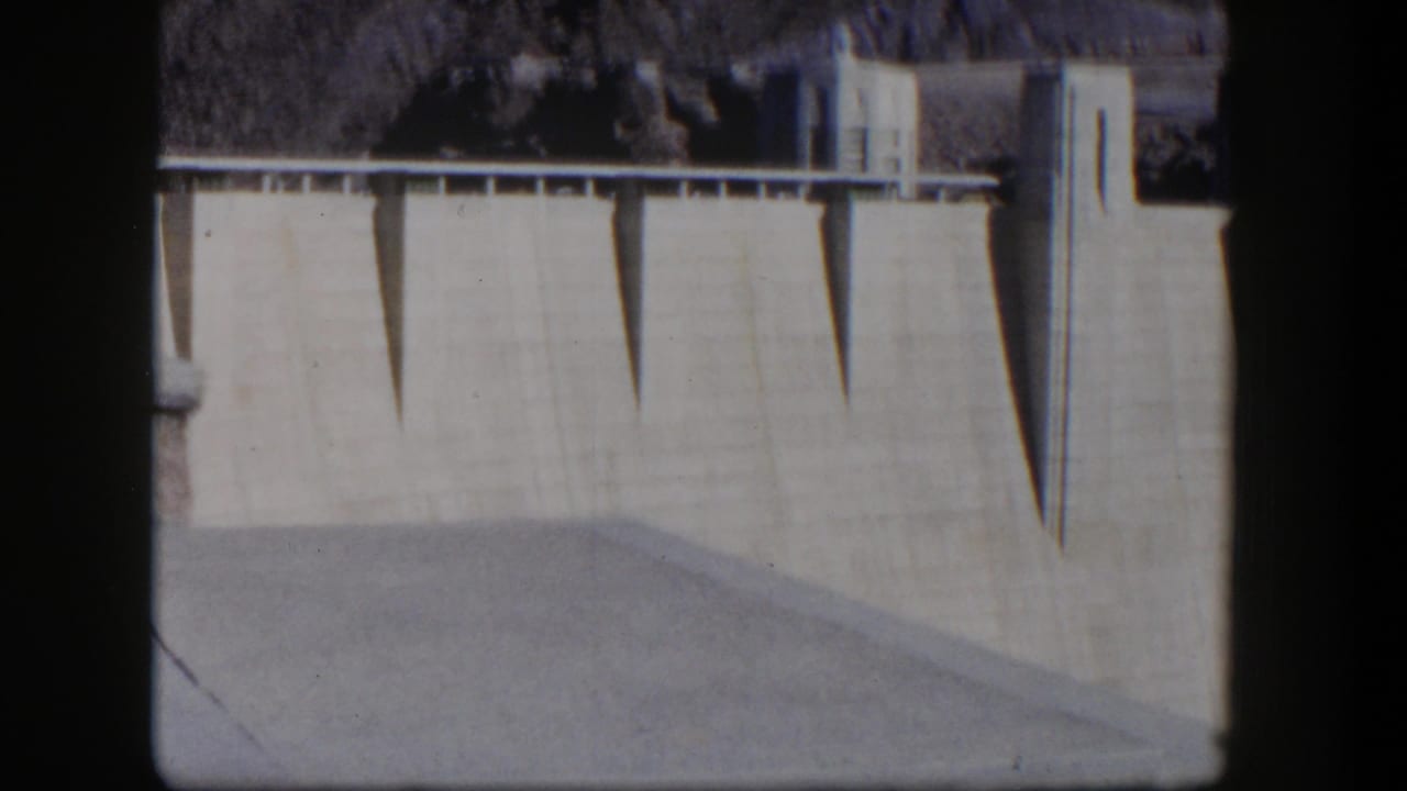 Close view of Hoover Dam's concrete wall with dark vertical shadows and film border.
