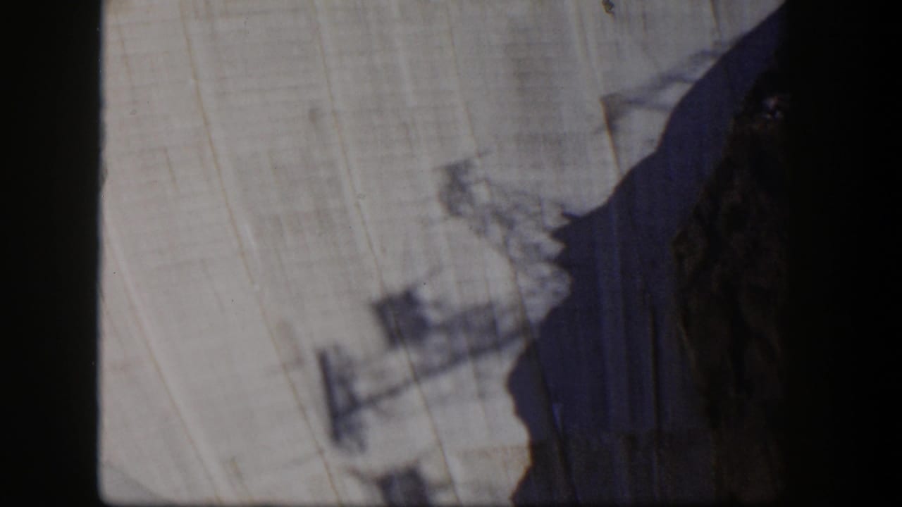 Pale cliff face with dark rock shadow and blurred foreground structure.