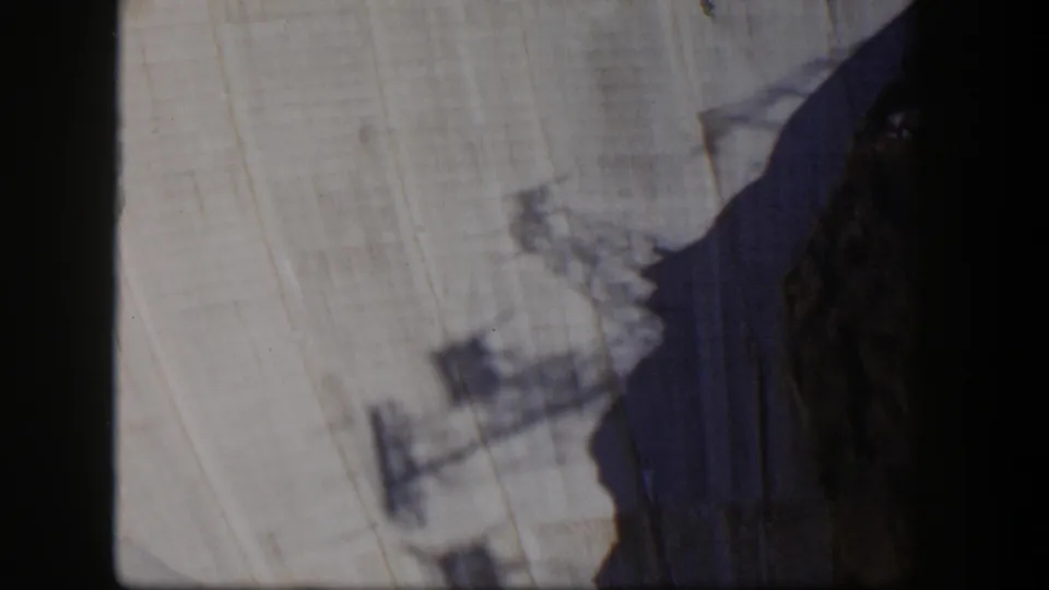 1954 Nevada 8mm frame showing a pale rocky cliff face partly obscured by dark rock and soft motion blur.