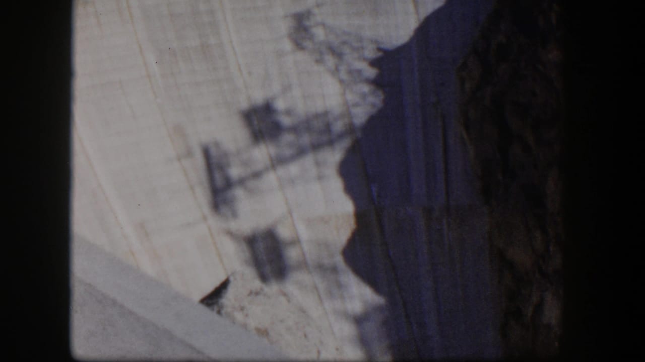 Light rock wall, dark cliff edge, and faint shadowed structural shapes.