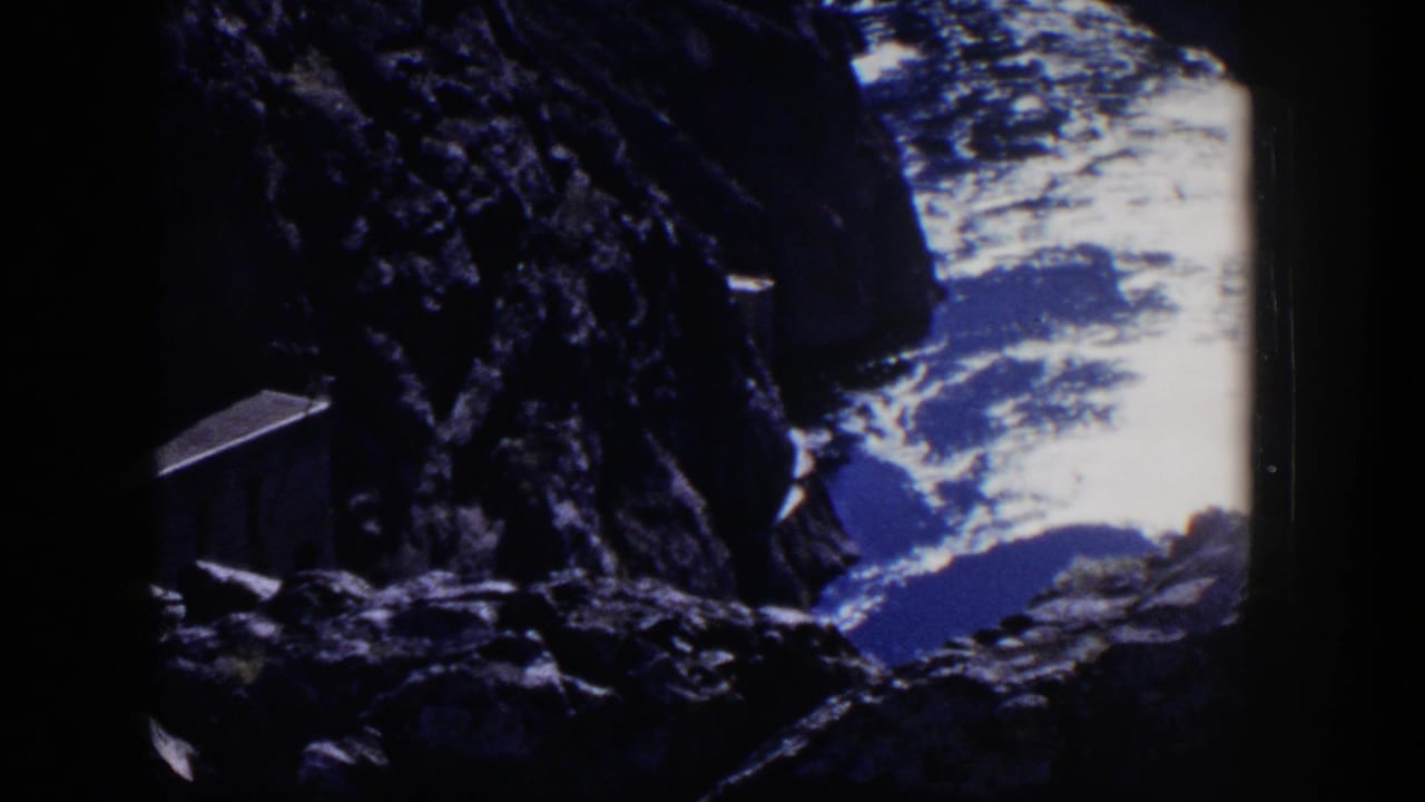Dark rocky cliff opening onto bright water below.