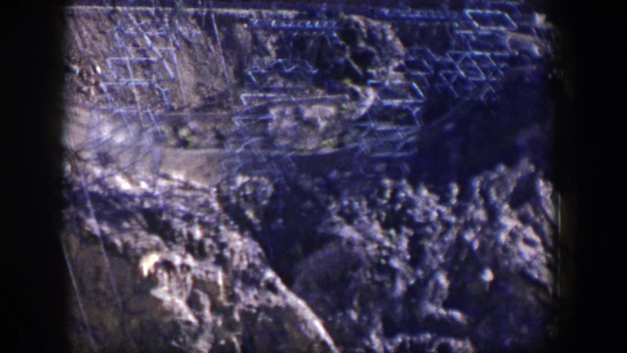 Transmission towers and power lines above rocky desert terrain.