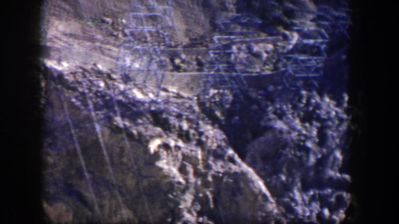 Power lines and tower structures crossing a rocky hillside.