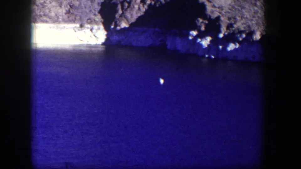 A second 1954 Nevada lake-view frame shows blue water, uneven rock forms, and strong dark borders from the 8mm scan.