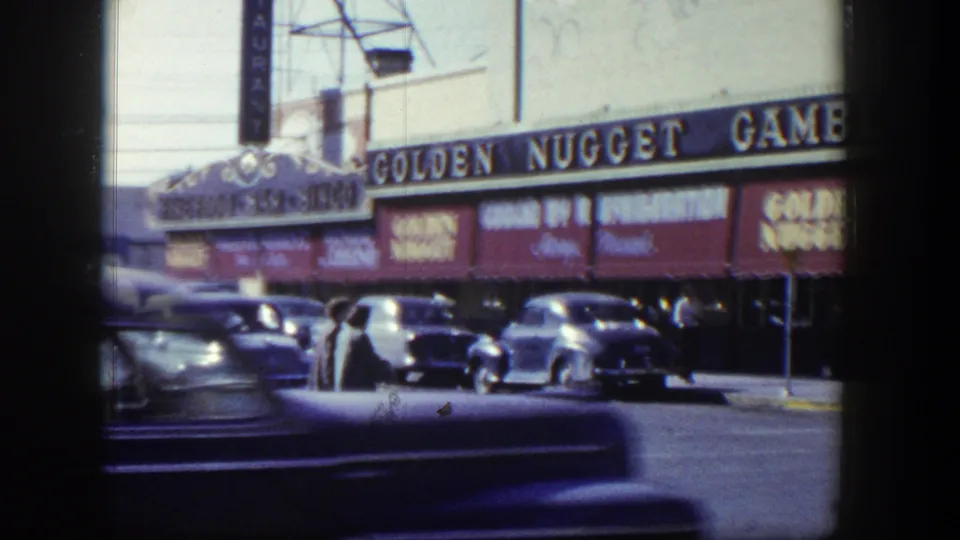 1954 Nevada street frame showing the Golden Nugget Gambling sign, red awnings, mid-century cars, and pedestrians near the curb.