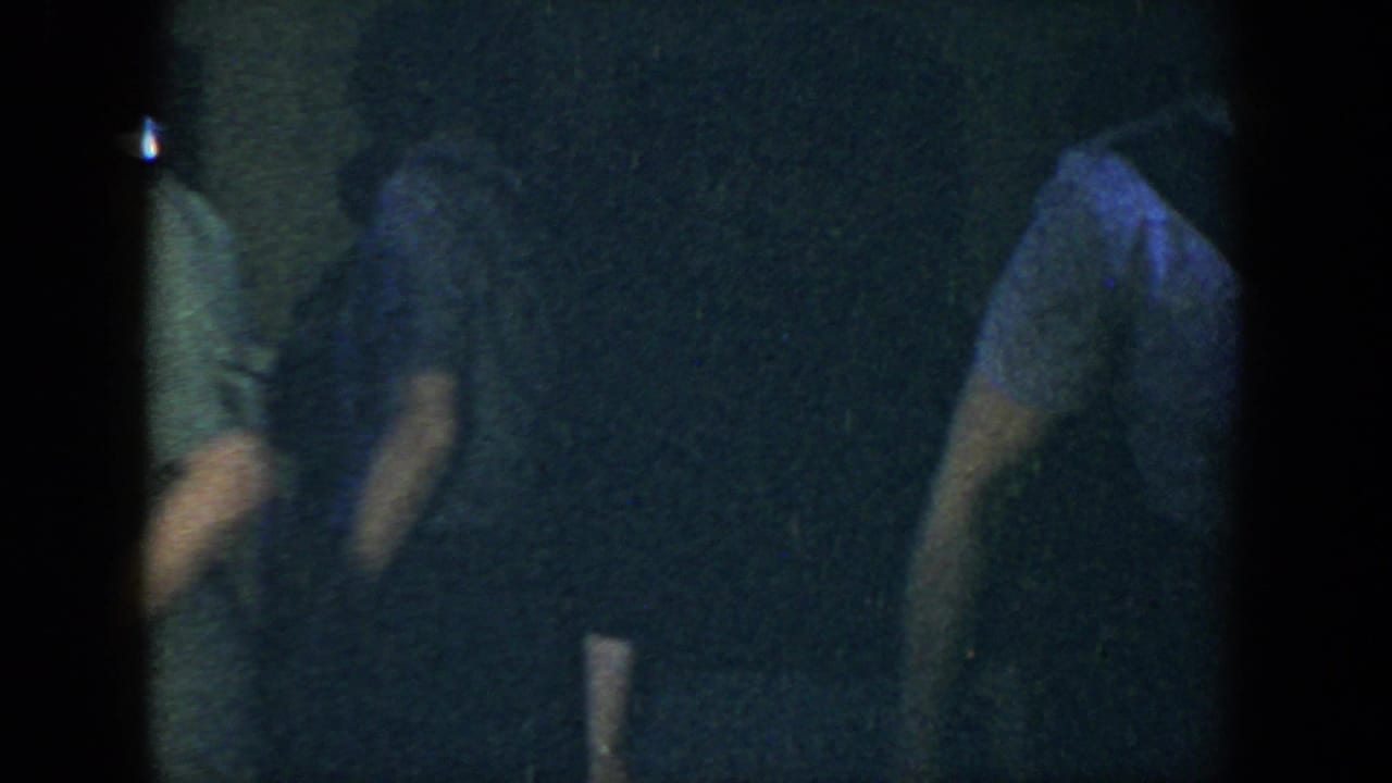 Woman in a dim room partly obscured by dark film edges.