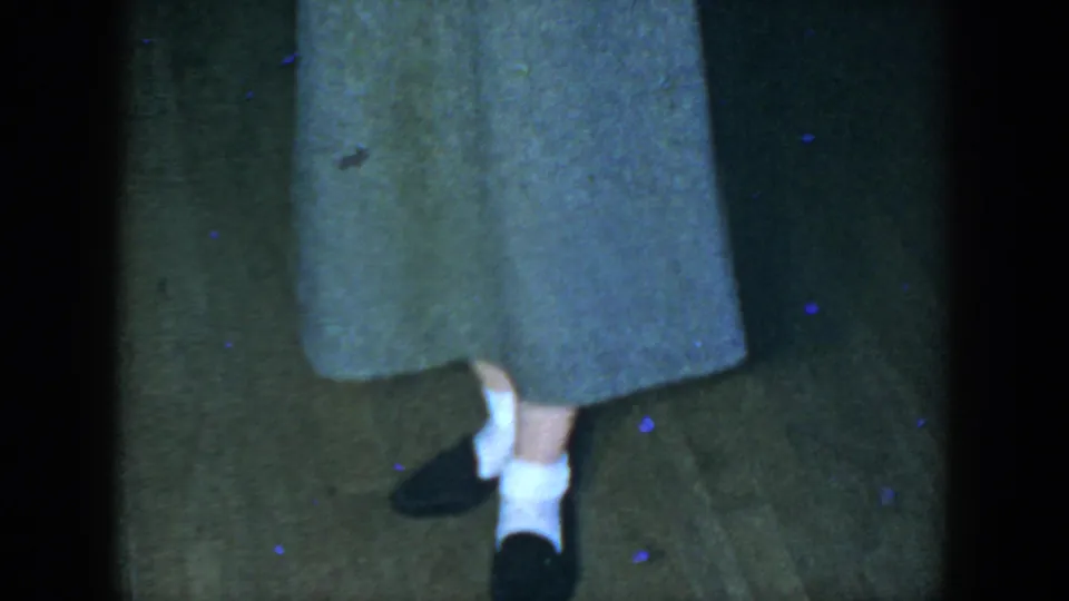 Near the end of the 1952 Houston clip, the woman stands facing the camera with her gray skirt and shoes clearly visible.