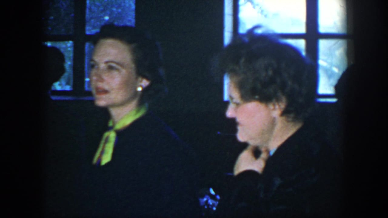 1952 Houston indoor gathering with two adult women near backlit windows, including one in a dark dress with a bright neck scarf.