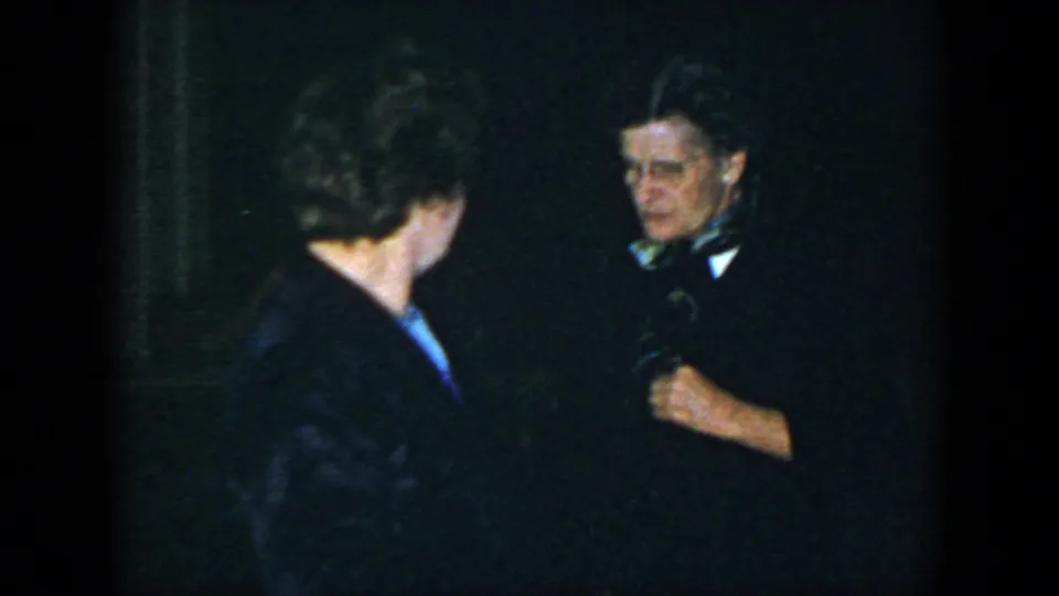In 1952 Houston home-movie footage, two adults in dark formal clothing appear in a flash-lit indoor party setting.