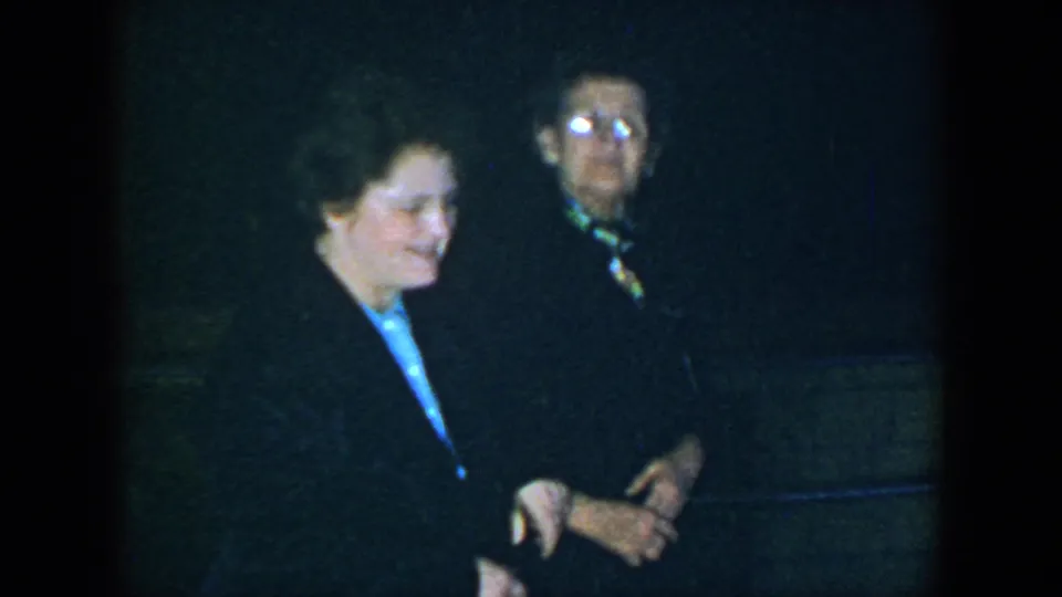 Two women in dark clothing stand together in grainy 1952 Houston nighttime home-movie footage.
