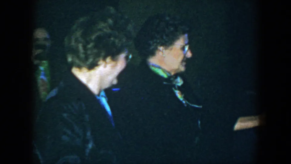 Two women appear in profile during a 1952 Houston indoor social scene, one wearing glasses and a green scarf.