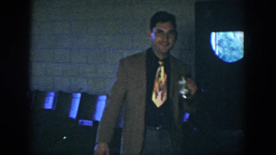 A second adult man appears in the 1952 Houston footage, wearing a brown jacket and colorful tie while holding a can in a dark interior.