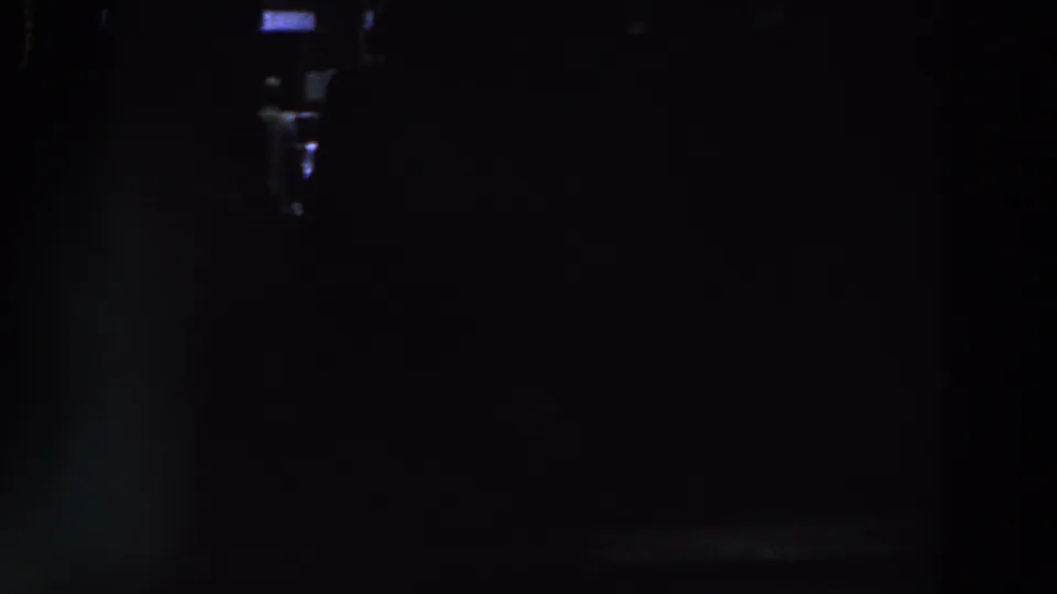 1961 Ireland 8mm frame showing a nearly black interior with small light patches and unclear human or architectural forms.