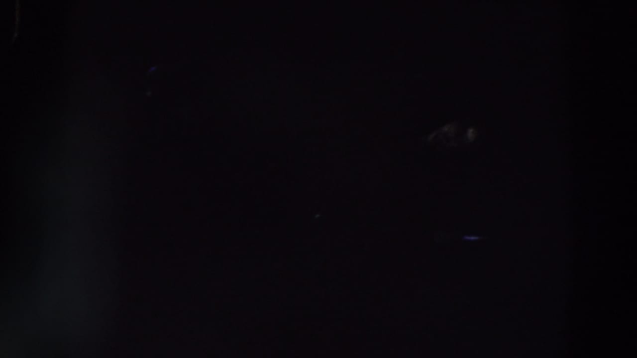 Dark 1961 Ireland 8mm frame with very faint silhouettes, blue flare, and little identifiable detail.