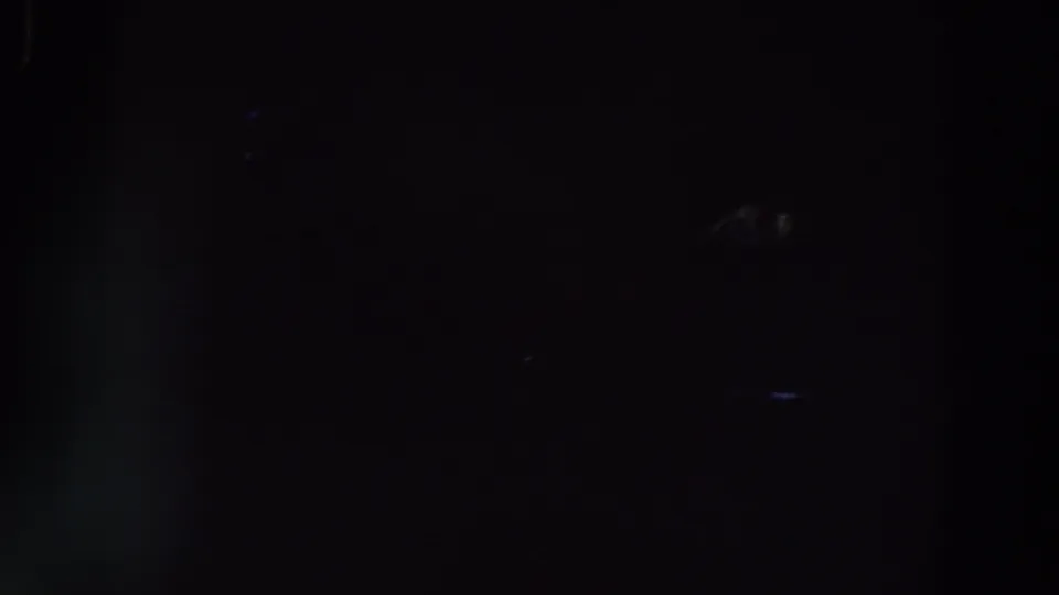 Dark 1961 Ireland 8mm frame with very faint silhouettes, blue flare, and little identifiable detail.