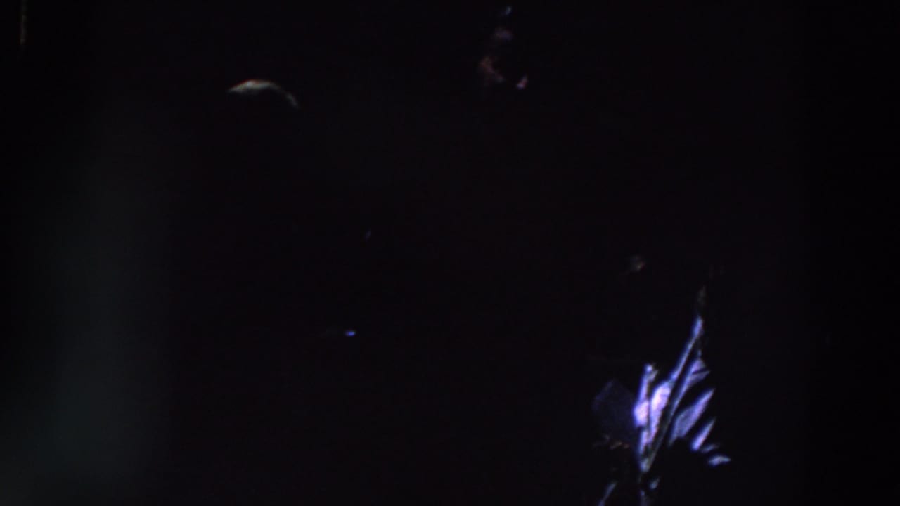 1961 Ireland 8mm frame showing a barely visible person in near darkness with a small blue-white highlight on clothing.