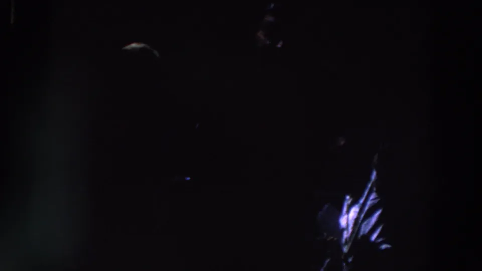 1961 Ireland 8mm frame showing a barely visible person in near darkness with a small blue-white highlight on clothing.