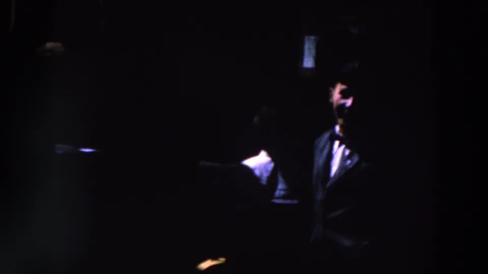 1961 Ireland frame with a suited or jacketed person partly lit beside another figure in heavy darkness.