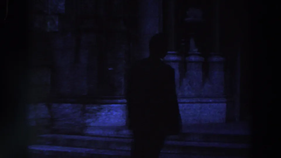 Dark 8mm frame of a silhouetted person on stone steps, likely from the same 1961 Ireland home-movie sequence.