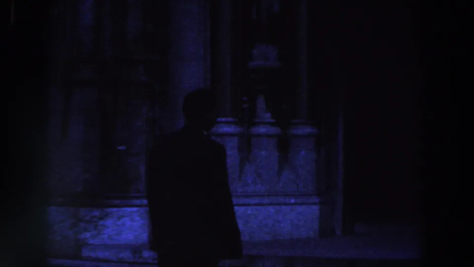 In 1961 Ireland footage, a suited man appears as a silhouette near stone columns and a dark doorway.