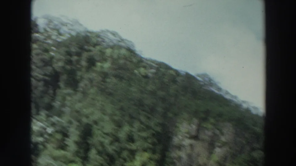 Motion-blurred Puerto Rico mountain view from the 1966 home movie, with the building edge and dark film border still visible.