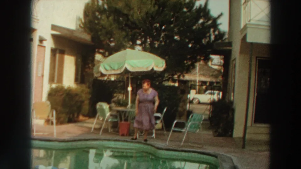 The woman appears to wave beside the swimming pool in 1966 Puerto Rico home-movie footage, with patio chairs behind her.