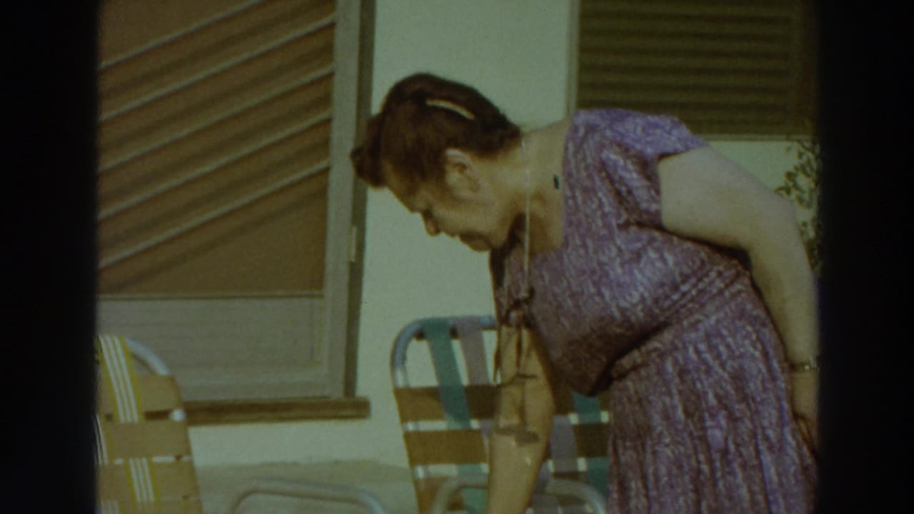 A woman in a purple patterned dress bends beside outdoor chairs on a sunny Puerto Rico patio in 1966 footage.
