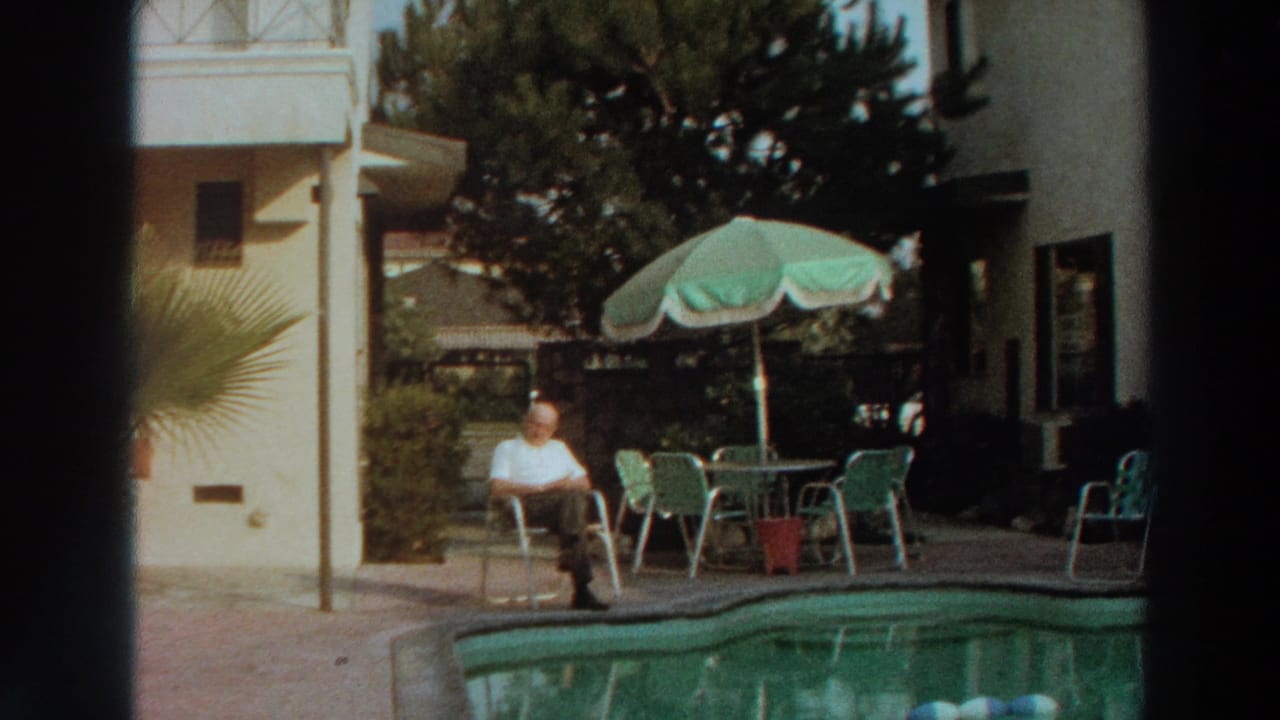 1966 Puerto Rico home-movie frame showing an elderly man seated near a pool with patio furniture and tropical plants.