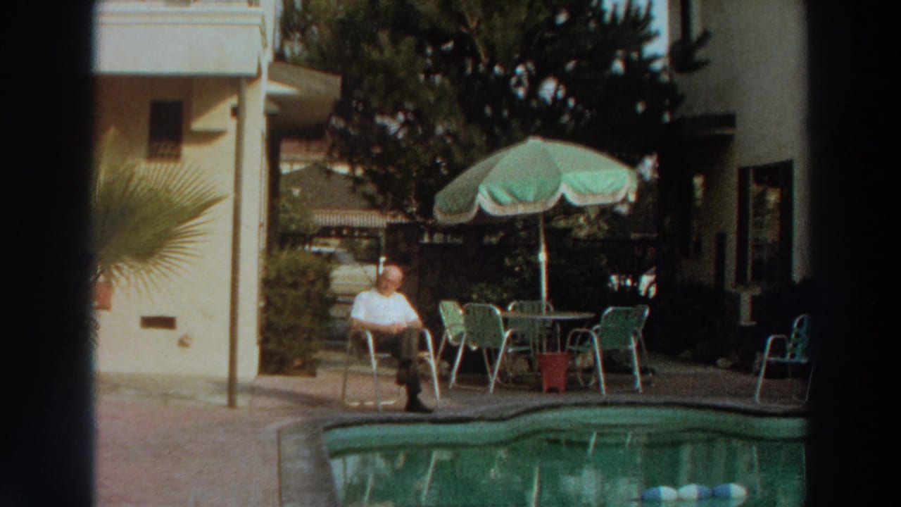 1966 Puerto Rico poolside view with a man resting alone near green patio furniture and a residential exterior.