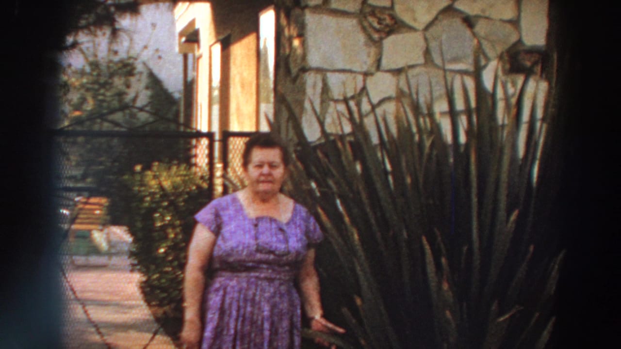 A closer 8mm frame shows the woman facing the camera in a purple dress, partly framed by tall garden plants outside the Puerto Rico residence.
