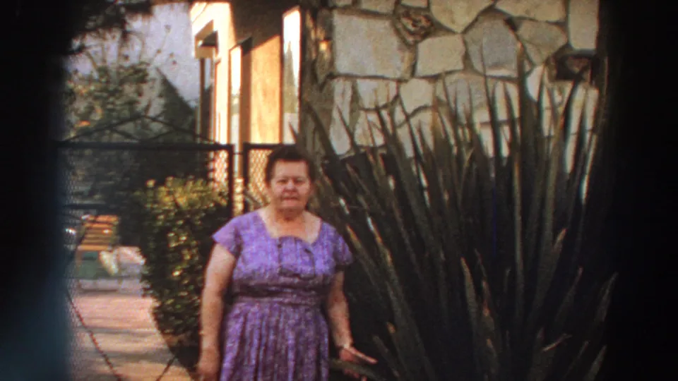 A closer 8mm frame shows the woman facing the camera in a purple dress, partly framed by tall garden plants outside the Puerto Rico residence.